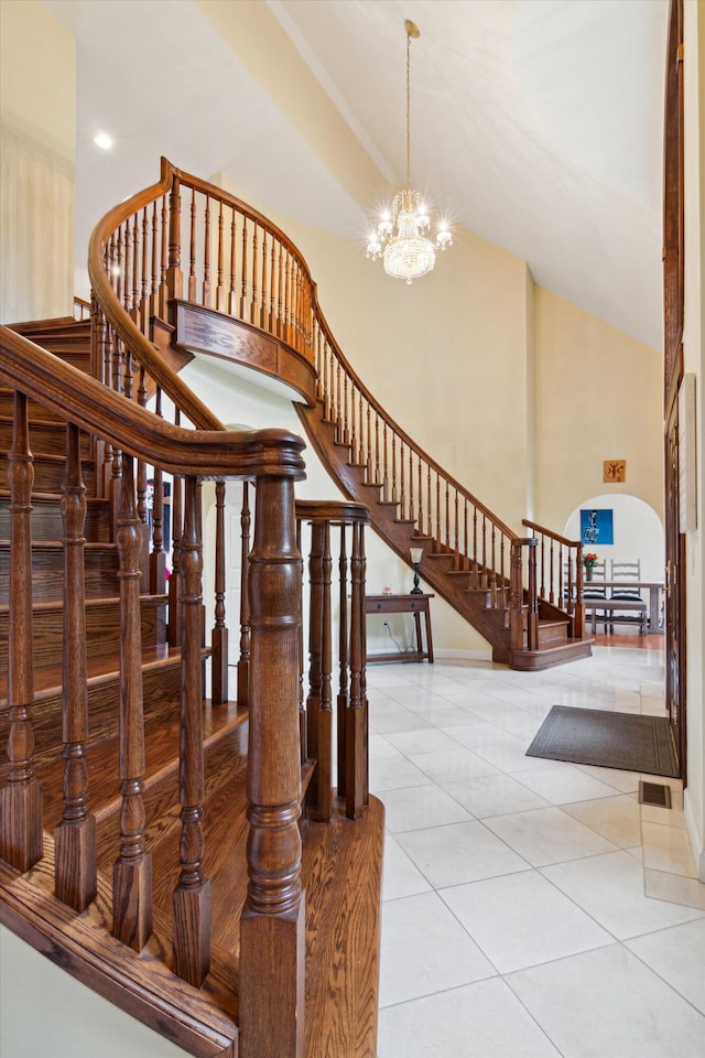 stairway with tile patterned floors, a notable chandelier, and vaulted ceiling