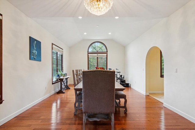 dining area featuring hardwood / wood-style floors, a chandelier, and vaulted ceiling