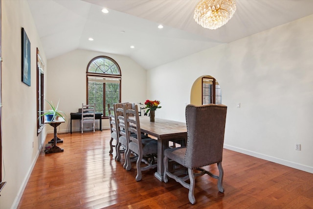 dining area with vaulted ceiling, an inviting chandelier, and hardwood / wood-style floors