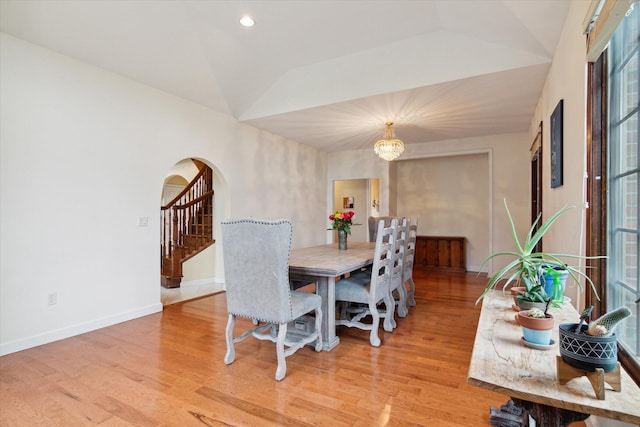 dining area with vaulted ceiling, a chandelier, and light hardwood / wood-style floors