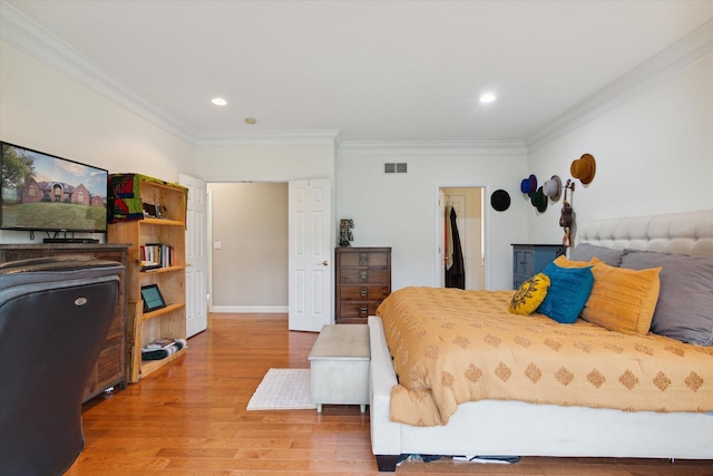 bedroom featuring a walk in closet, ornamental molding, and hardwood / wood-style flooring