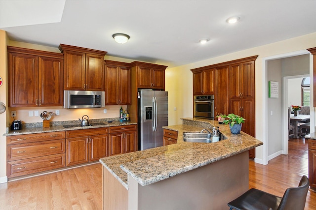 kitchen featuring a kitchen bar, sink, appliances with stainless steel finishes, and a kitchen island with sink