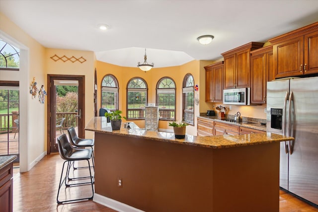 kitchen featuring decorative light fixtures, a breakfast bar, stainless steel appliances, and an island with sink