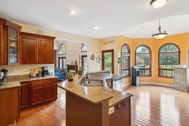 kitchen with dishwasher, sink, hanging light fixtures, a kitchen island with sink, and light hardwood / wood-style flooring