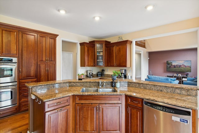 kitchen with light stone countertops, sink, stainless steel appliances, and hardwood / wood-style floors