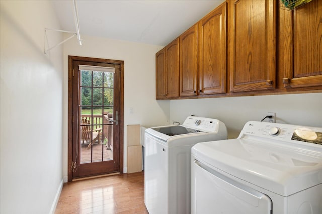 laundry area with washing machine and dryer, cabinets, and light wood-type flooring