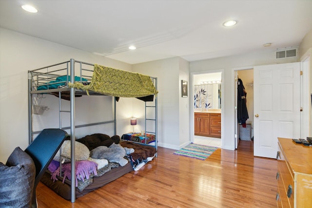 bedroom with hardwood / wood-style floors, a walk in closet, a closet, and ensuite bath