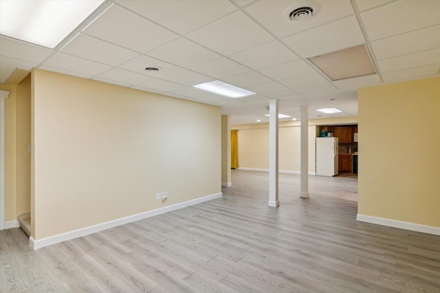 basement featuring white fridge, light hardwood / wood-style flooring, and a drop ceiling