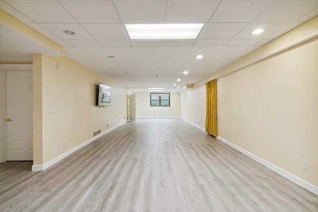 basement featuring a paneled ceiling and light hardwood / wood-style flooring