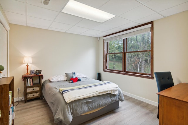 bedroom featuring light hardwood / wood-style floors and a drop ceiling