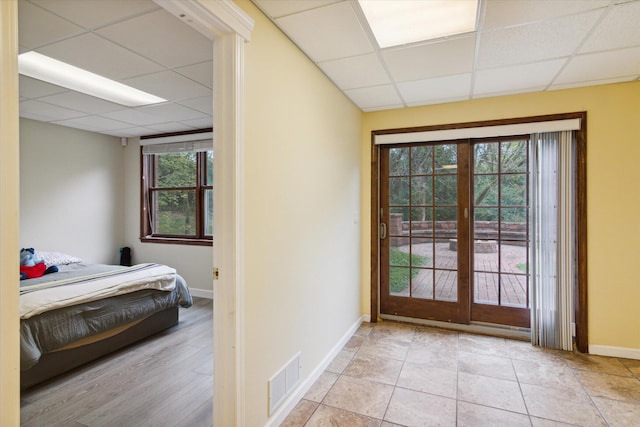 doorway with a healthy amount of sunlight, a drop ceiling, and french doors