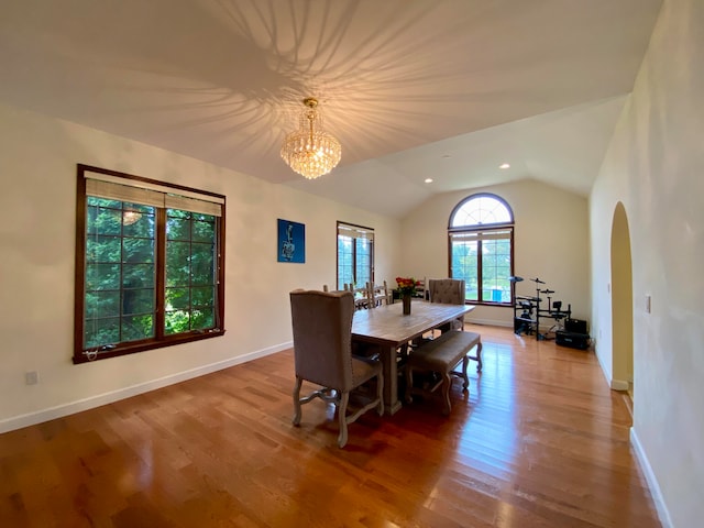 dining space featuring lofted ceiling, wood-type flooring, and a chandelier