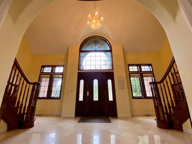 tiled entryway with a towering ceiling and an inviting chandelier