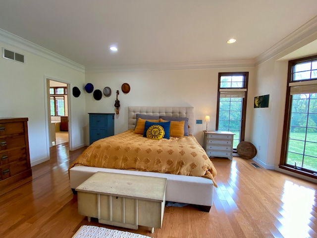 bedroom with multiple windows, crown molding, and light wood-type flooring