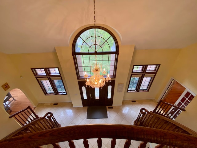 foyer with an inviting chandelier, tile patterned flooring, and a high ceiling