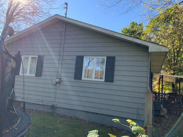 view of side of home with a deck and a trampoline