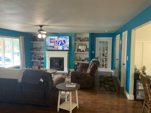 living room featuring ceiling fan, a textured ceiling, and dark hardwood / wood-style flooring