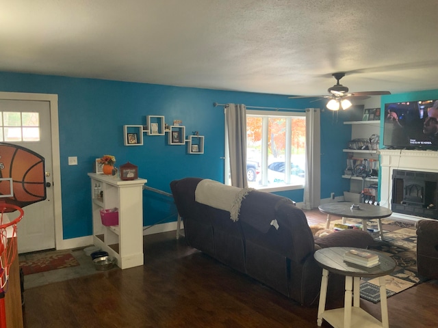 living room with a textured ceiling, ceiling fan, and dark hardwood / wood-style flooring