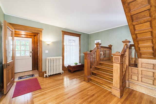 foyer featuring light hardwood / wood-style flooring, crown molding, and radiator heating unit