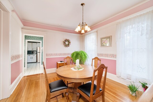 dining room with an inviting chandelier, hardwood / wood-style floors, and ornamental molding