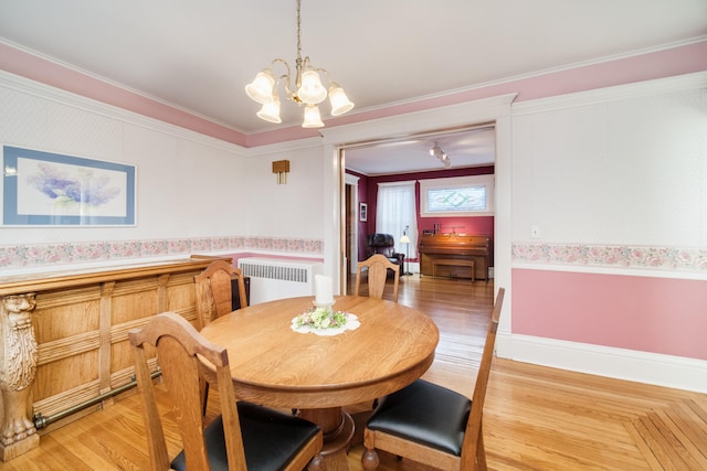 dining area featuring radiator heating unit, crown molding, a notable chandelier, and light hardwood / wood-style floors