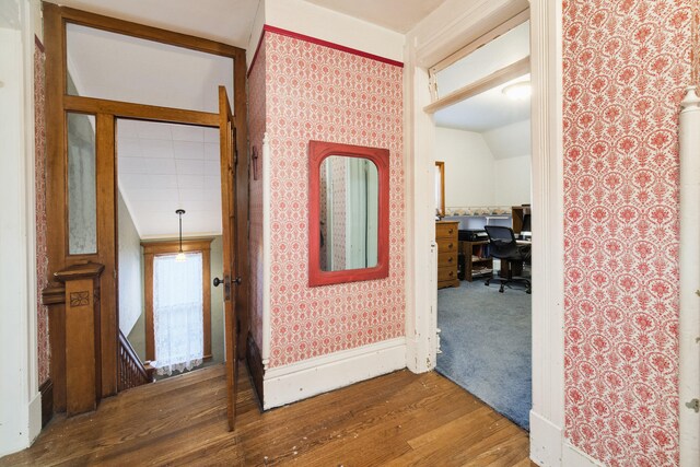 corridor with dark hardwood / wood-style floors and vaulted ceiling