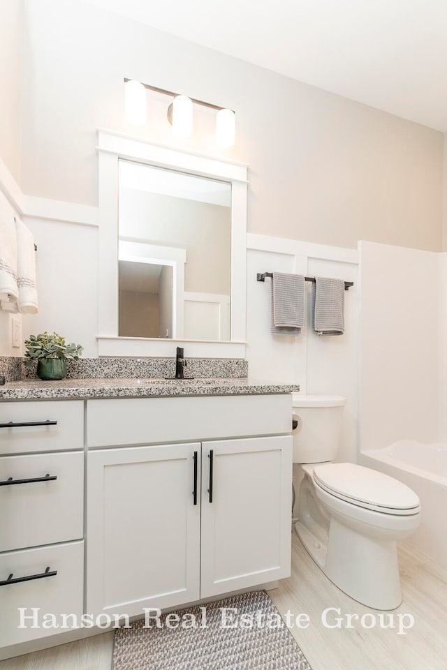 bathroom with wood-type flooring, vanity, and toilet