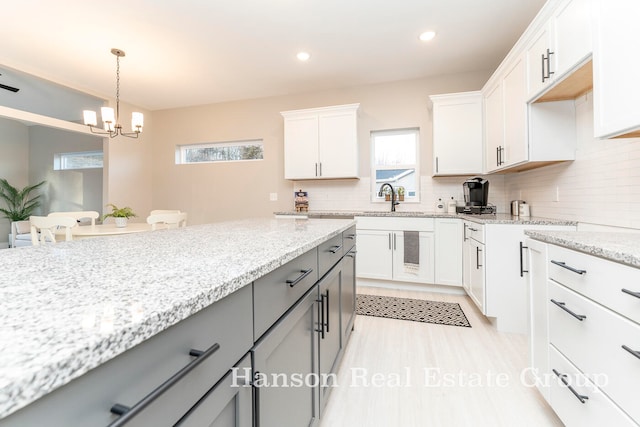 kitchen featuring gray cabinetry, white cabinetry, a chandelier, and plenty of natural light