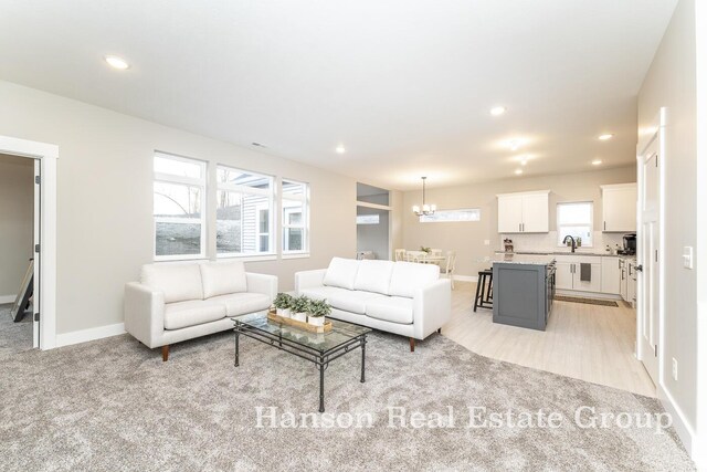 living room with light colored carpet, a chandelier, and sink