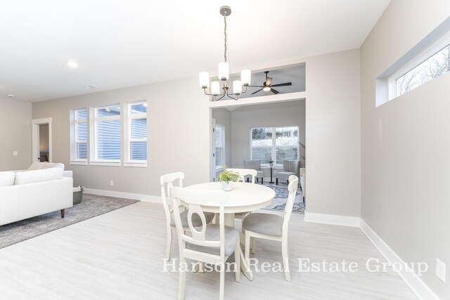 dining room featuring ceiling fan with notable chandelier, light hardwood / wood-style flooring, and plenty of natural light