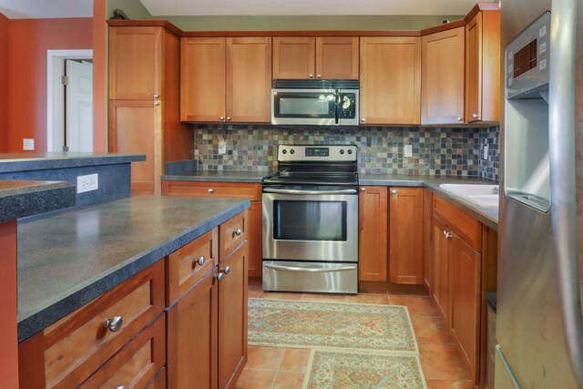 kitchen with backsplash, sink, light tile patterned floors, and stainless steel appliances