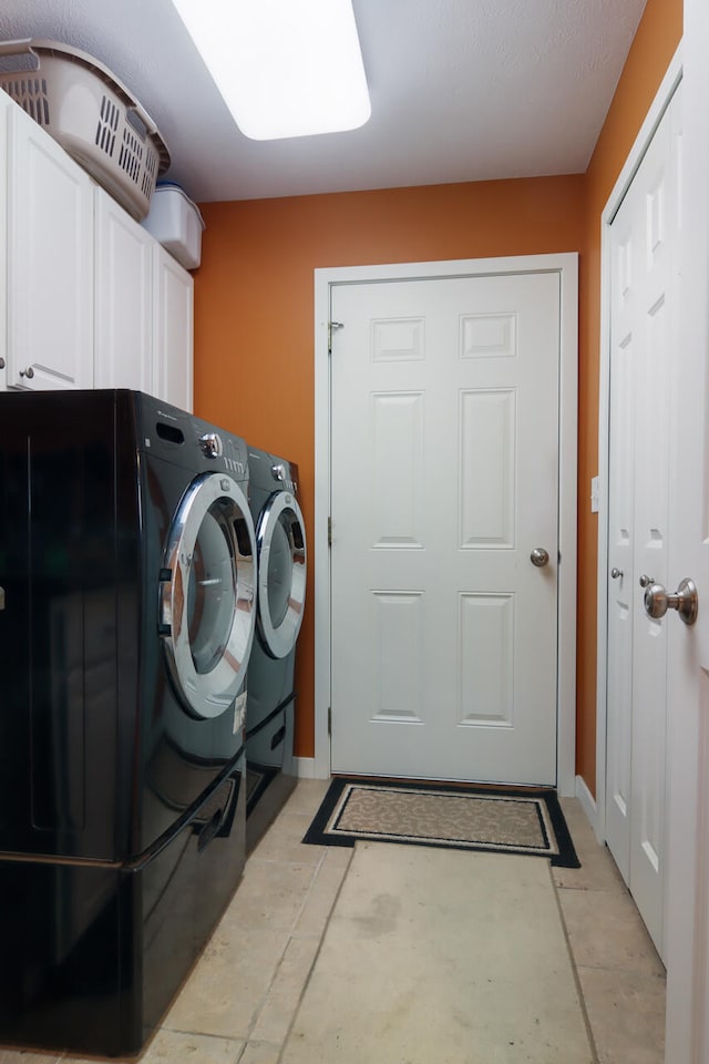 clothes washing area featuring washing machine and dryer and cabinets