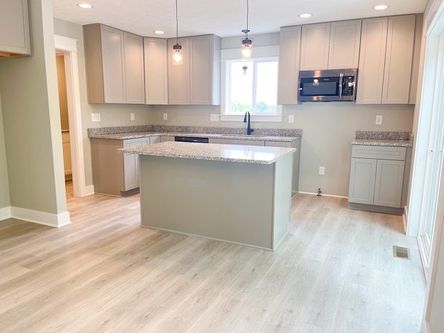 kitchen with pendant lighting, gray cabinets, stainless steel appliances, and light wood-type flooring