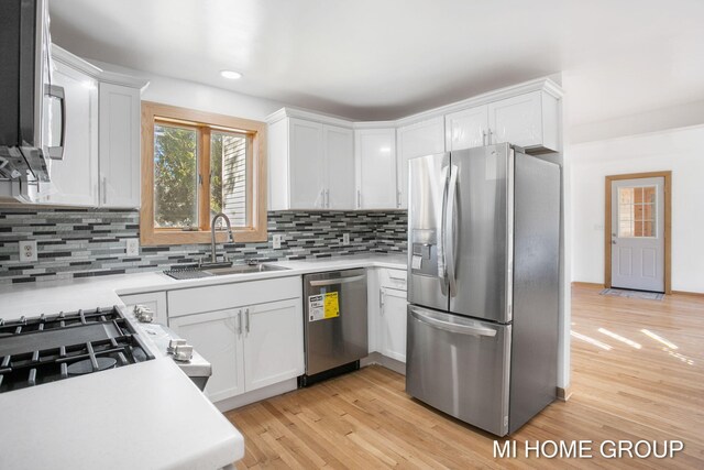 kitchen with decorative backsplash, white cabinetry, sink, and stainless steel appliances