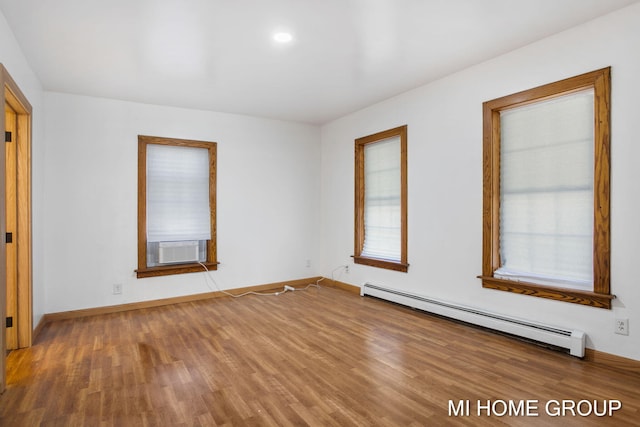 unfurnished room featuring hardwood / wood-style floors, cooling unit, and baseboard heating