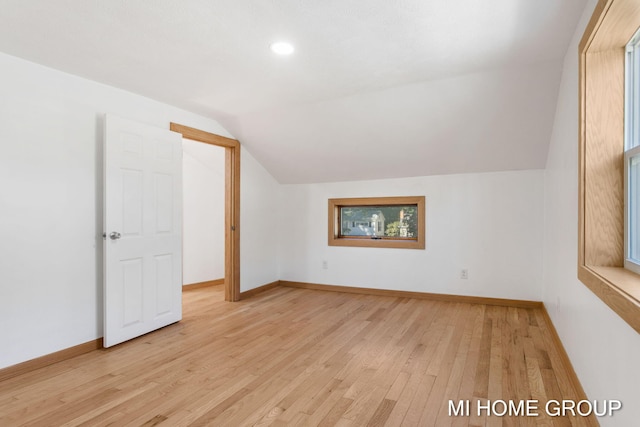 additional living space with light hardwood / wood-style floors and vaulted ceiling