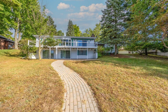 rear view of property with a lawn and a balcony