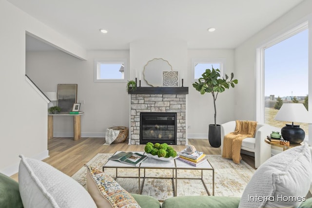 living area featuring recessed lighting, a fireplace, baseboards, and wood finished floors