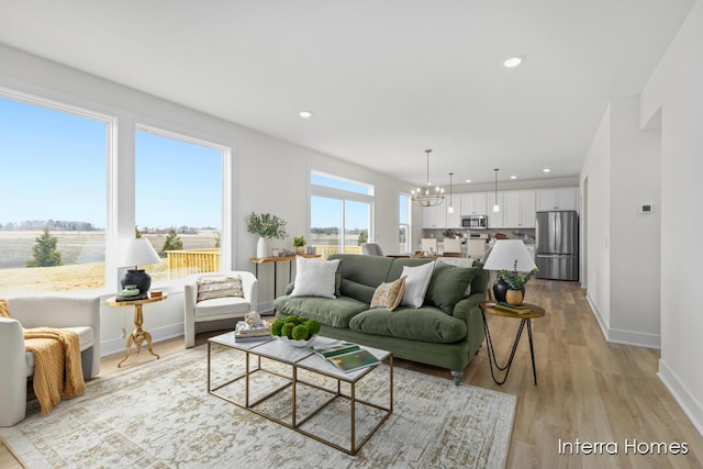 living room with a chandelier, a wealth of natural light, light wood-style flooring, and recessed lighting