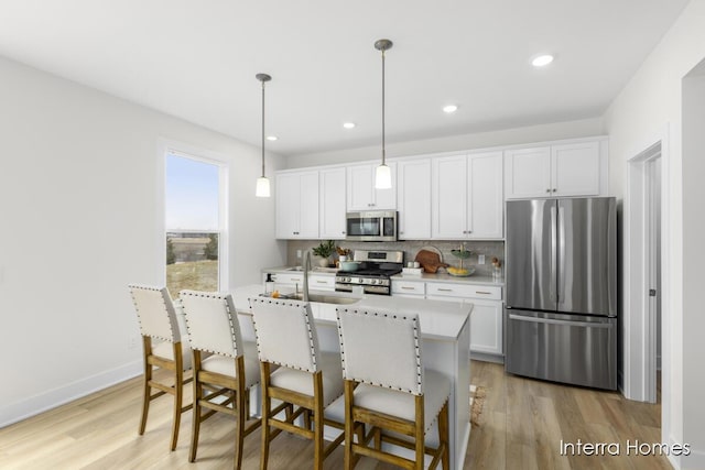 kitchen featuring a sink, light countertops, appliances with stainless steel finishes, light wood-type flooring, and backsplash