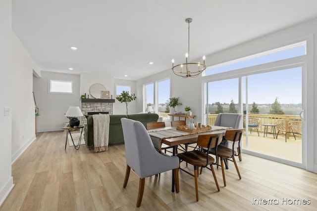 dining space with light wood finished floors, a fireplace, recessed lighting, and a healthy amount of sunlight