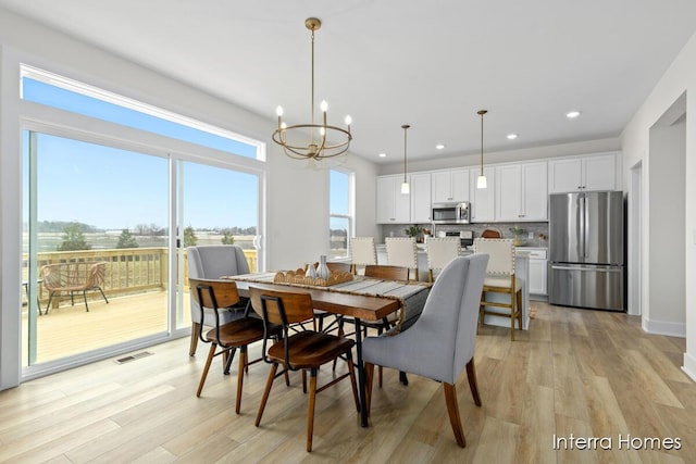 dining space featuring light wood finished floors, recessed lighting, visible vents, and an inviting chandelier