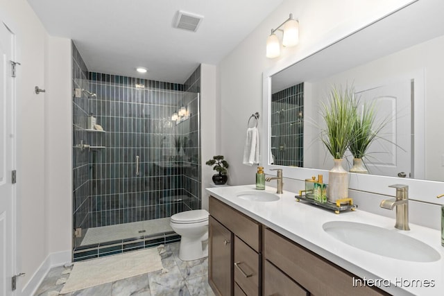 full bathroom with double vanity, tiled shower, a sink, and toilet