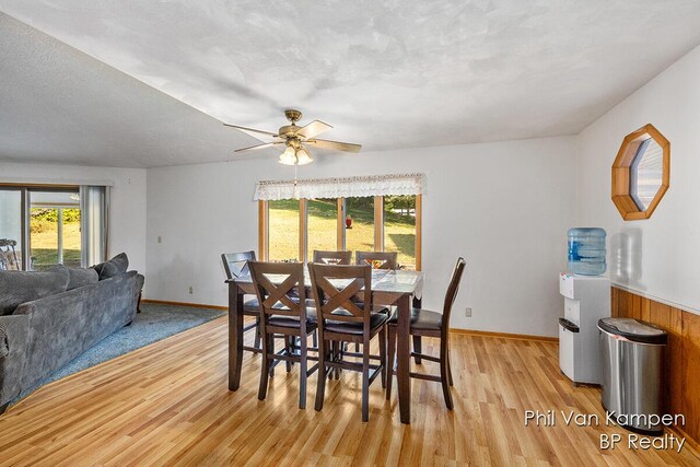 dining space with baseboards, light wood-style floors, ceiling fan, and a textured ceiling