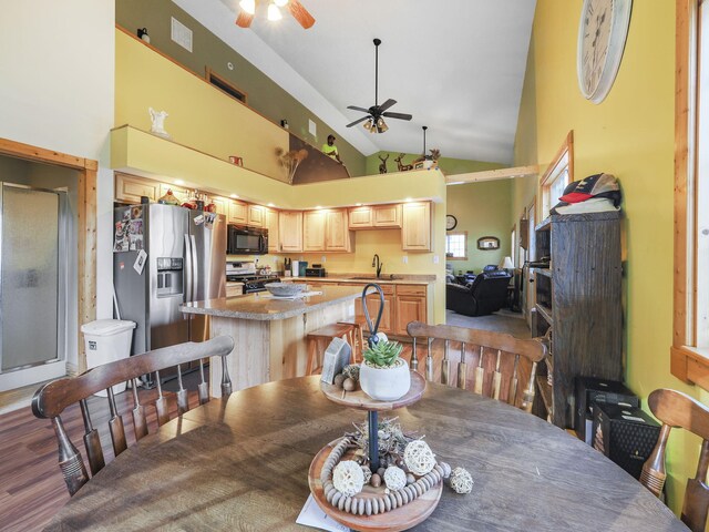 dining area with high vaulted ceiling, wood-type flooring, sink, and ceiling fan