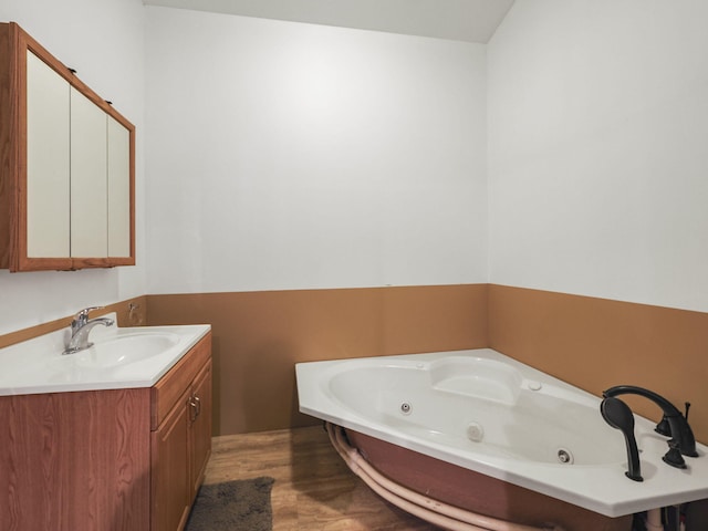 bathroom featuring vanity, a washtub, and hardwood / wood-style floors