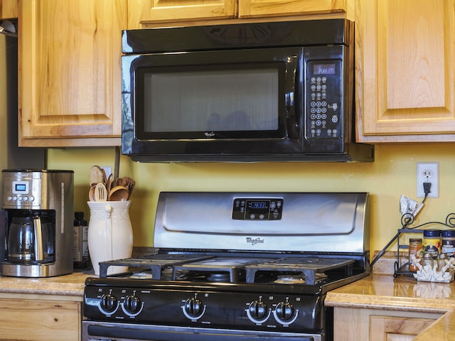 details featuring light brown cabinetry, black appliances, and light stone counters