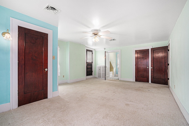 unfurnished bedroom with ceiling fan, light colored carpet, and ensuite bathroom