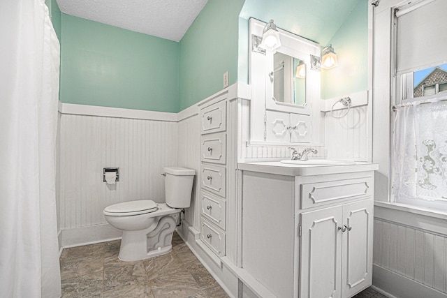 bathroom with a textured ceiling, lofted ceiling, vanity, and toilet