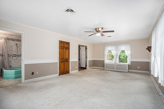 spare room with carpet floors, crown molding, radiator, and ceiling fan